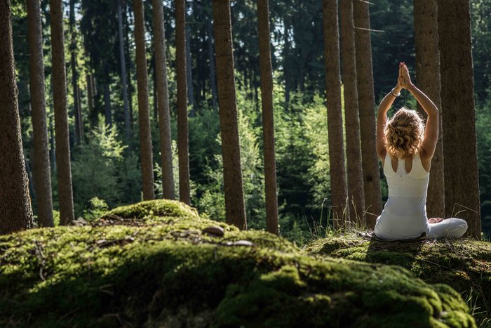 Eine Frau praktiziert Yoga im Wald