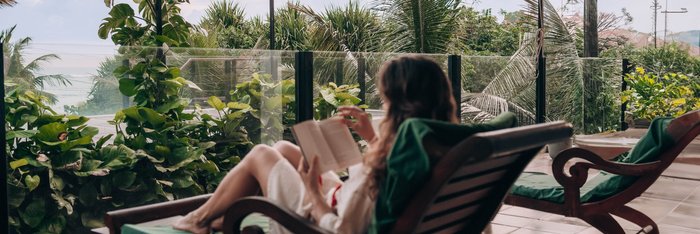Eine Frau liest ein Buch auf dem Balkon
