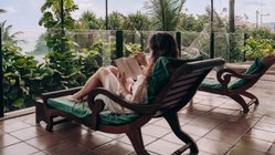 Eine Frau liest ein Buch auf dem Balkon