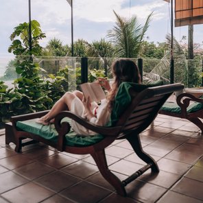 Eine Frau liest ein Buch auf dem Balkon