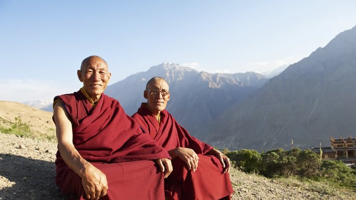 Zwei Mönche sitzen auf einem Berghang im Schneidersitz