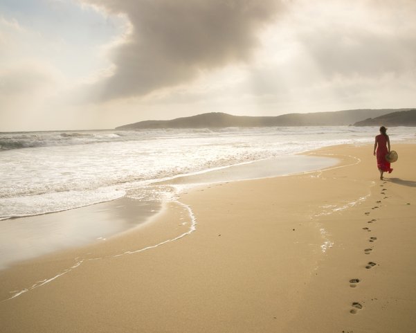 Eine Frau spaziert an einem einsamen Strand in der Dämmerung