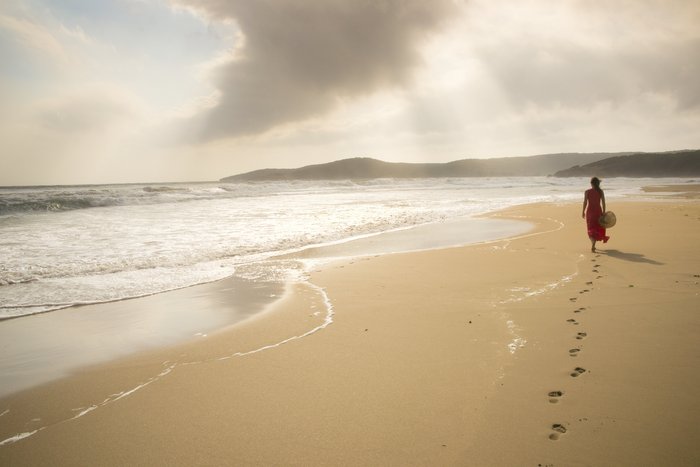 Eine Frau spaziert an einem einsamen Strand in der Dämmerung