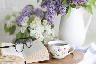 Ein Tablet mit einer Tasse Kaffee und einem Buch mit einer Brille drauf