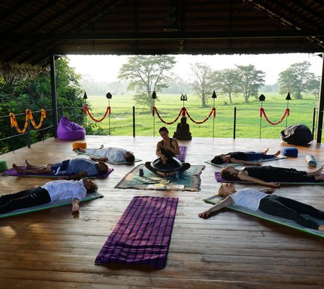 Yogis in Shavasana auf einer Yogaplattform