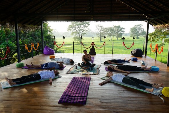 Yogis in Shavasana auf einer Yogaplattform