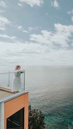 Eine Frau steht auf der Terrasse des Alpino Atlantico uns blickt auf das Meer