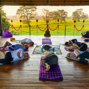 Eine Gruppe an Yogis liegt in Seitenposition in einem Kreis