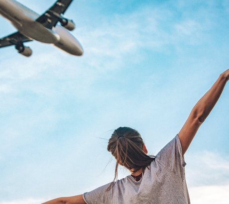 Eine Frau ahmt ein Flugzeug in der Luft nach