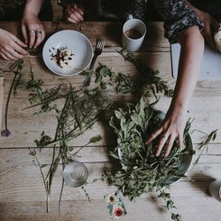 Mehrere Hände an einem Tisch mit Kräutern und Butter