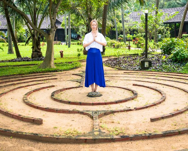 Eine Frau steht in einem Garten die Hände in anjali mudra