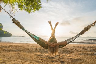 Eine junge Frau liegt auf einer Hängematte an einem tropischen Strand