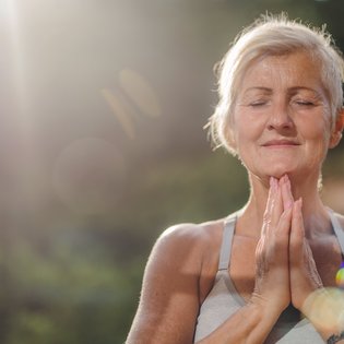 Eine Seniorin hält die Hände im Anjali Mudra