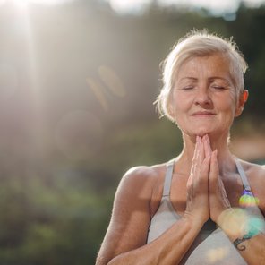 Eine Seniorin hält die Hände im Anjali Mudra