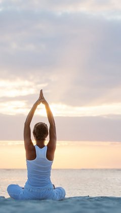 Eine Frau übt Yoga am Strand