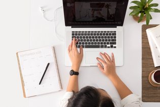 Frau sitzt mit einem Laptop am Schreibtisch