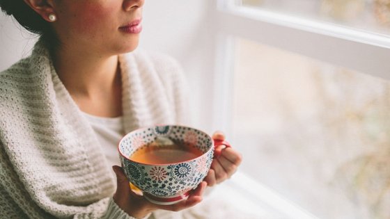 Frau mit einer Tasse Tee am Fenster