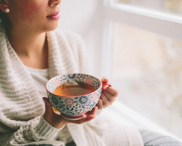 Frau mit einer Tasse Tee am Fenster