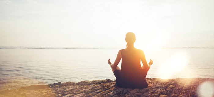 Eine Frau übt Meditation am Meer