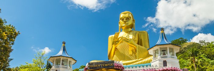 Goldene Buddha-Statue die auf einem bunten Tempel sitzt 