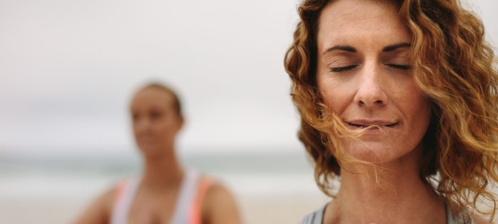 Ein Mann und eine Frau meditieren im stehen an einem Strand